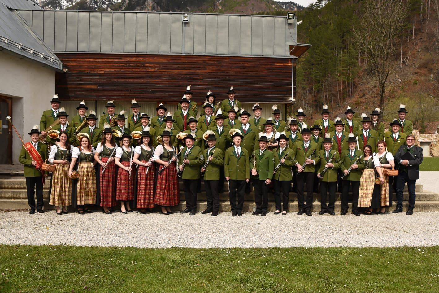 Eine Gruppe von Musikern in traditioneller Kleidung, mit Musikinstrumenten, posiert für ein Foto vor einem Gebäude.