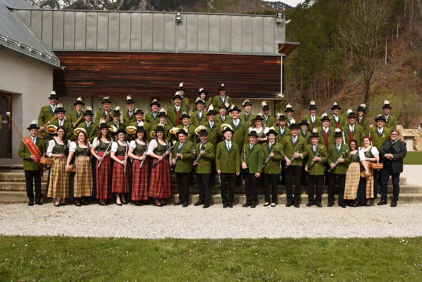 Eine Gruppe von Musikern in traditioneller Kleidung, mit Musikinstrumenten, posiert für ein Foto vor einem Gebäude.
