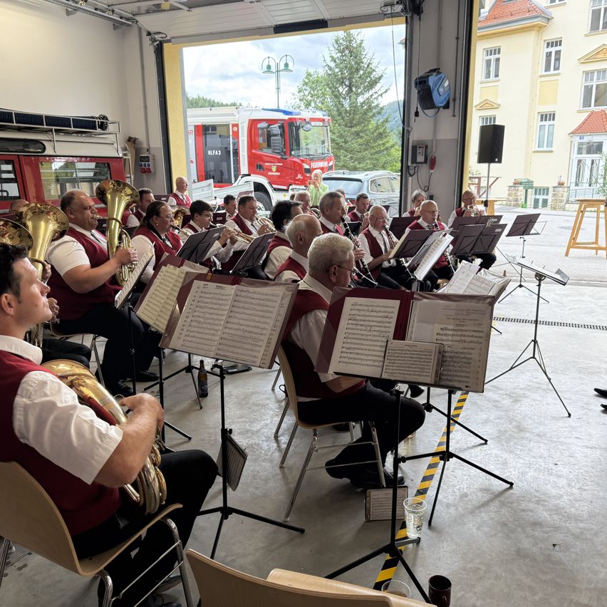 Blasorchester spielt im Feuerwehrhaus mit rotem Feuerwehrauto im Hintergrund