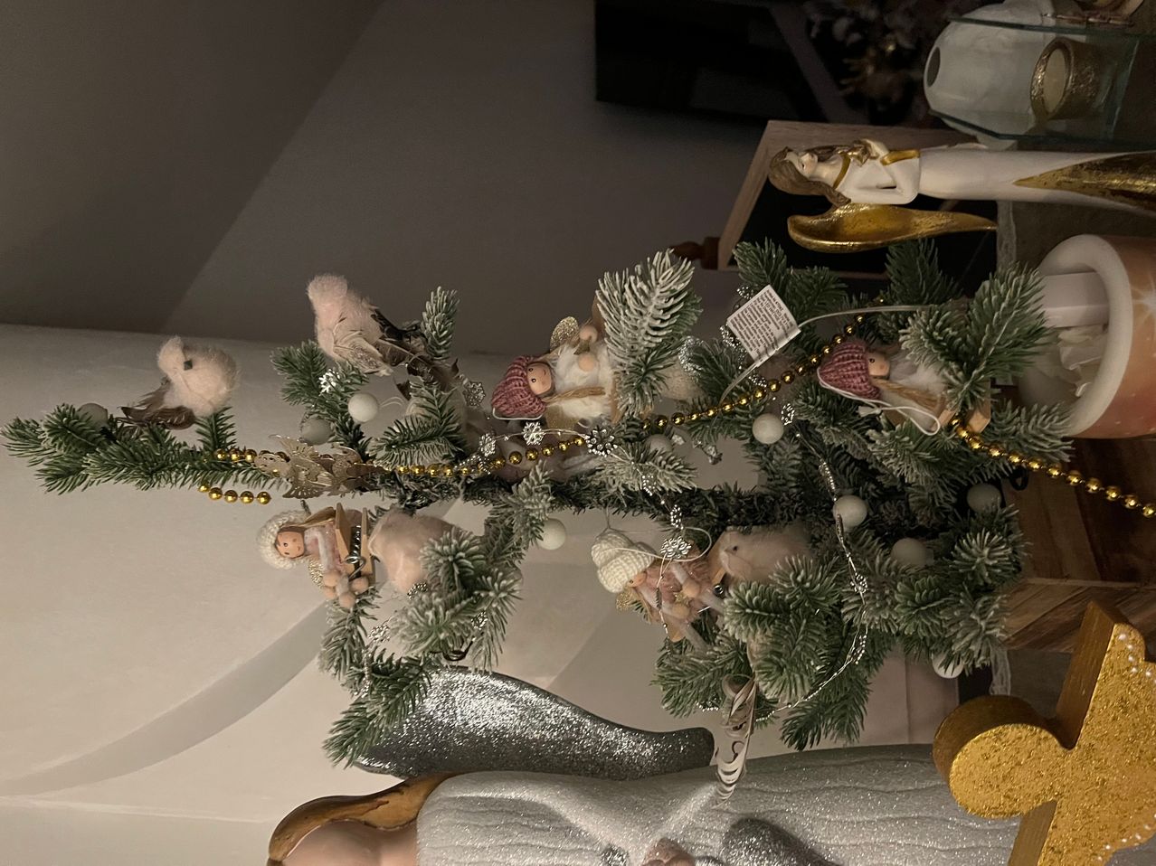 Ein geschmückter Weihnachtsbaum mit Engelsfiguren, Perlen und Ornamenten. Verschiedene Engel sitzen auf den Ästen, und ein goldener Engel sitzt oben.