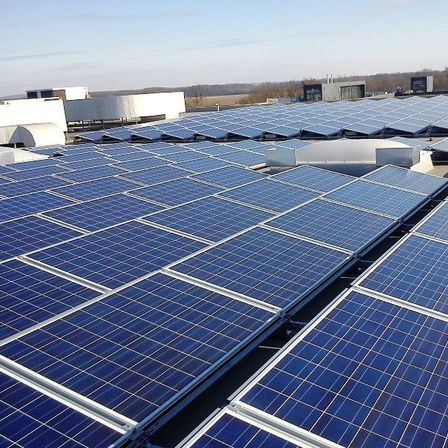 Eine große Solarpanel-Anlage auf einem Dach unter einem klaren blauen Himmel.