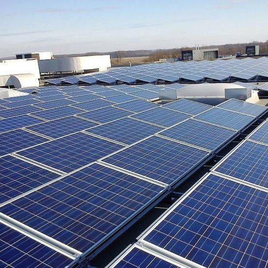 Eine große Solarpanel-Anlage auf einem Dach unter einem klaren blauen Himmel.