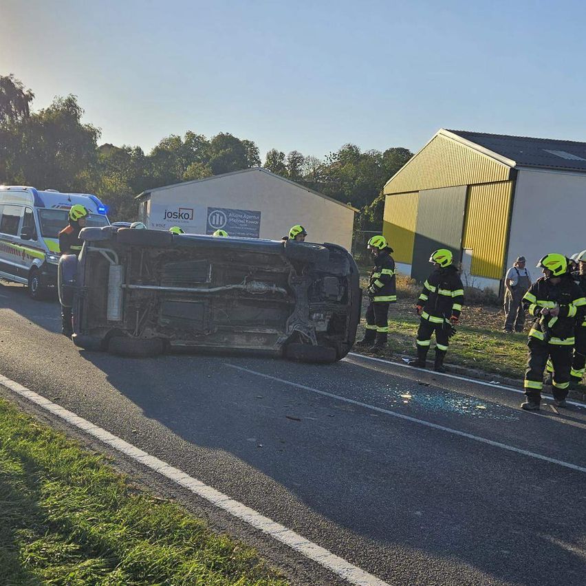 Ein umgestürztes Auto am Straßenrand mit Rettungsfahrzeugen und Feuerwehrleuten, die den Unfallort versorgen.