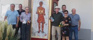 Eine Gruppe von Menschen posiert für ein Foto vor einer bemalten Telefonzelle mit einem Vogel obenauf und den Worten Les Art Bucherbox.