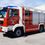 Freiwillige Feuerwehr Edelsdorf-Logo. Ein roter Feuerwehrwagen mit weißen Streifen und blauen Lichtern auf der Oberseite steht auf einem Parkplatz.