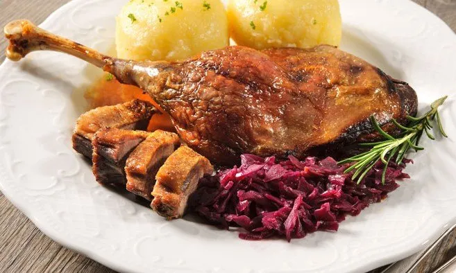 Ein Teller mit gebratener Ente, Kartoffeln, Kraut und Rosmarin.