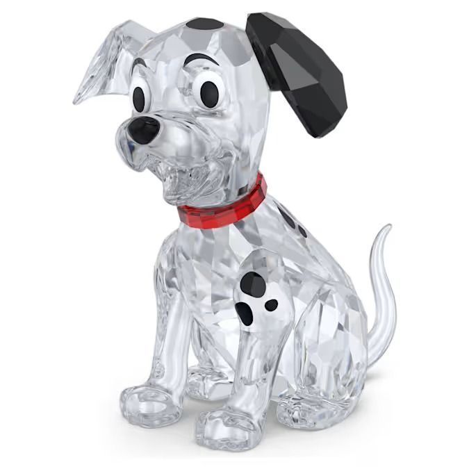 Eine Kristallfigur eines Hundes, der auf einem weißen Hintergrund sitzt. Der Hund hat ein rotes Halsband und schwarze Flecken auf seinem Körper.
