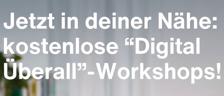 Eine Hand hält ein Stück Papier mit einem pixeligen Händedruckbild, über einem Laptop. Der Text lautet 'Jetzt in Ihrer Nähe: kostenlose 'Digital overall'-Workshops!'. Ein Bücherregal und eine Tasse sind im Hintergrund.