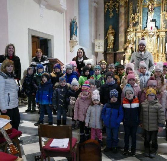 Eine Gruppe von Erwachsenen und Kindern steht lächelnd für die Kamera in einer Kirche.