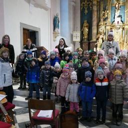 Eine Gruppe von Erwachsenen und Kindern steht lächelnd für die Kamera in einer Kirche.