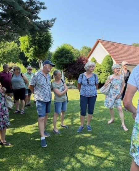 Eine Gruppe Erwachsener steht auf einem Rasen, wahrscheinlich auf einer Tour, mit einem Haus im Hintergrund.