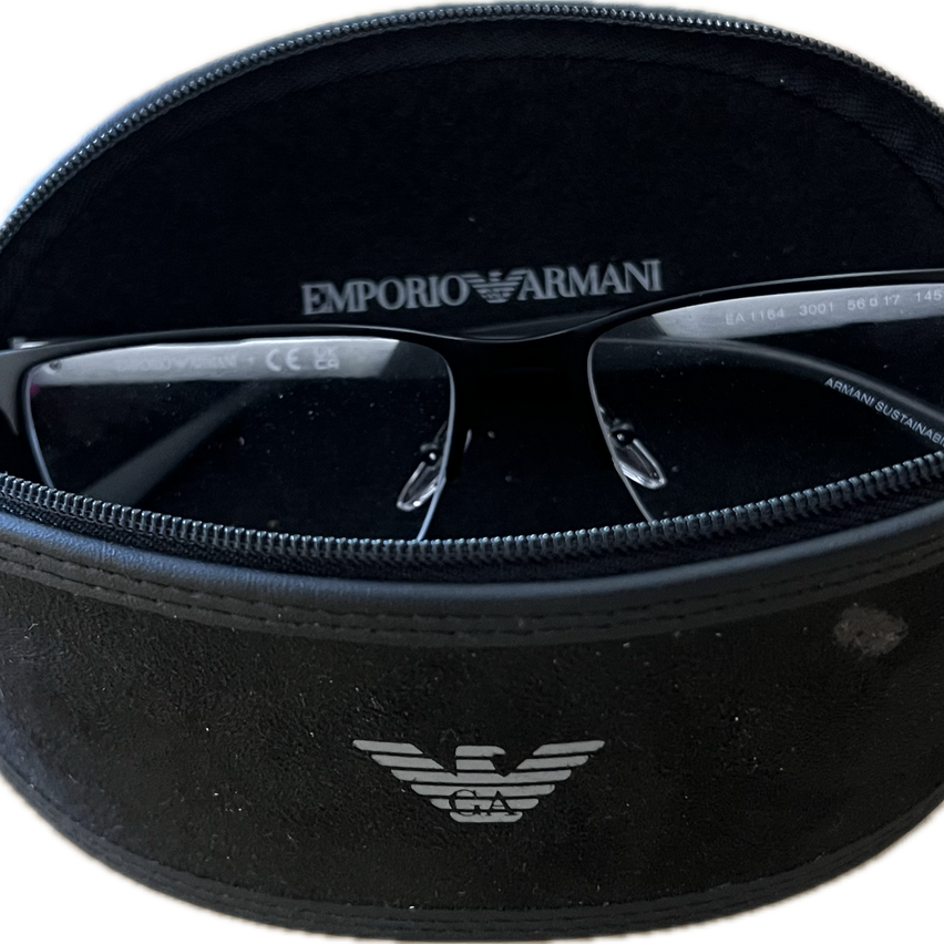 Ein schwarzes Emporio Armani Brillenetui mit Logo auf der Vorderseite. Im Inneren befindet sich ein Paar Emporio Armani-Brillen mit dem Markennamen auf den Bügeln eingraviert.