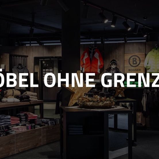 Ein Bekleidungsgeschäft mit Holzwänden und Deckenlampen. Ausgestellte Kleidung umfasst Jacken, Mützen und Schals. Ein Tisch hat einen Korb mit Gegenständen, und ein Holzschild mit dem Text 'Bogner' ist sichtbar.