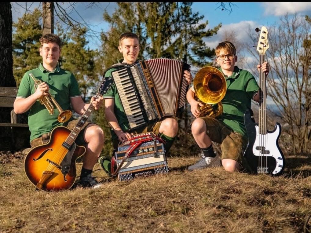 Drei junge Musikanten mit Instrumenten in Tracht in freier Natur