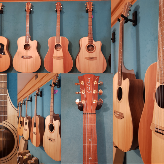 Ein Collage von akustischen Gitarren, die an einer blauen Wand ausgestellt sind. Verschiedene Modelle und Oberflächen sind zu sehen. Die Gitarren hängen und stehen, einige mit Preisschildern.