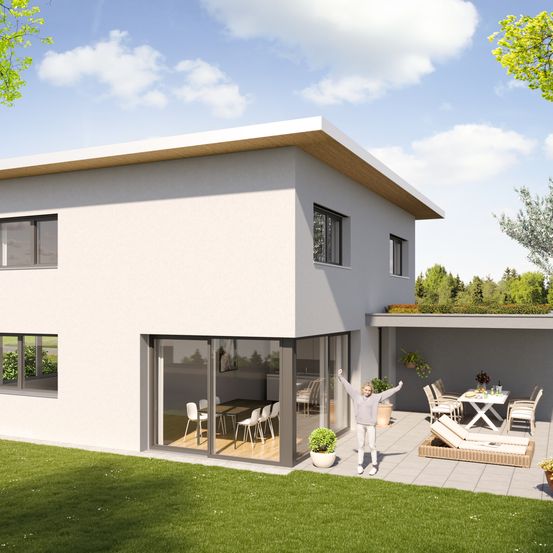 Ein modernes weißes Haus mit Glastüren und Fenstern, das einen großen Garten mit Terrasse, Stühlen, einem Tisch und einem Mädchen, das steht und lächelt, aufweist.