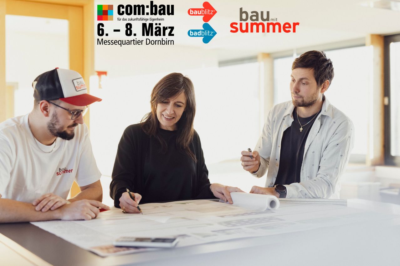 Four people are gathered around a desk with architectural plans. A woman smiles while looking at a man. The man looks at something on the right. They seem to be discussing something. There is a logo in the upper left corner.