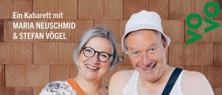 Zwei Menschen posieren für ein Foto. Der Mann hält eine Flasche und einen Hot Dog. Die Frau lächelt. Das Bild hat einen Slogan, 'SCHAFFA SCHAFFA HUELE BAU'. Das Bild hat einen Wasserzeichen auf der linken unteren Seite.