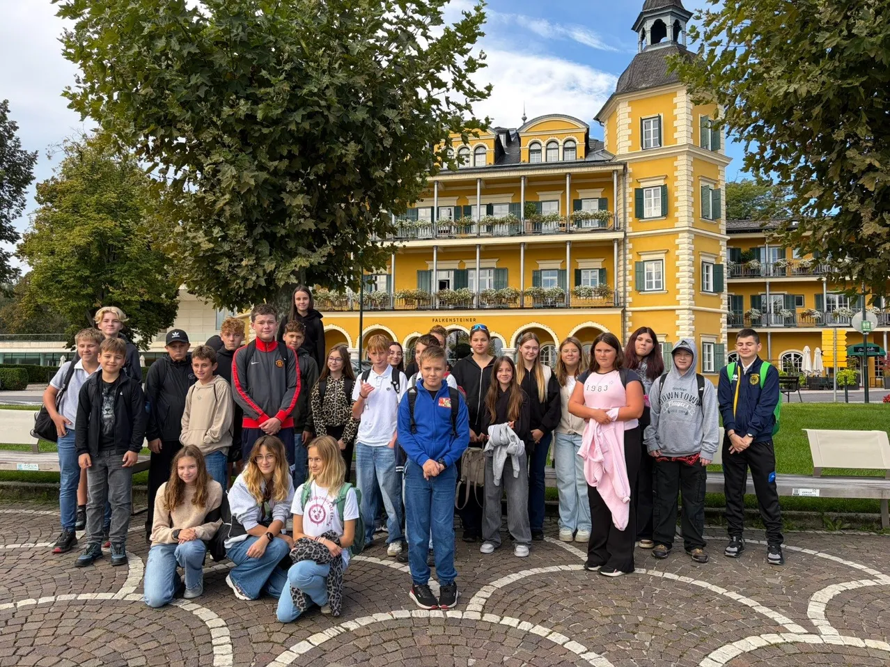 Eine Gruppe junger Menschen posiert für ein Foto vor einem gelben Gebäude.