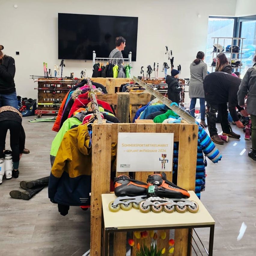 Ein Geschäft mit verschiedenen Jacken zur Schau, einem Tisch mit Rollschuhen und stöbernden Leuten. Ein Fernseher ist an der Wand montiert, und Helme stehen auf einem Regal.