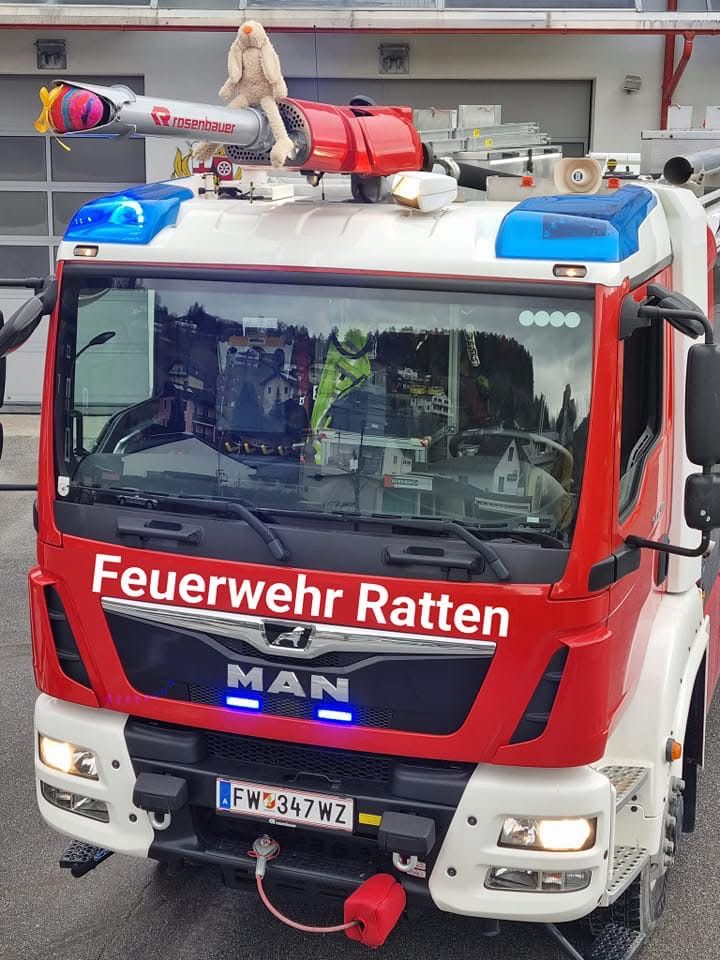 Ein roter MAN Feuerwehrwagen aus Ratten steht mit eingeschalteten Lichtern in einer Garage.