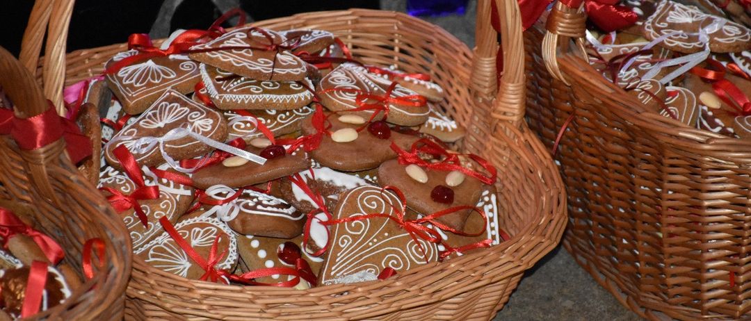 Ein Korb aus Weide gefüllt mit kunstvoll verzierten Lebkuchen, einige mit roten Bändern und weißer Glasur, und ein weiterer Korb im Hintergrund.
