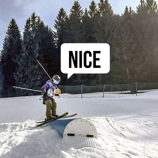 Ein Skifahrer mit Helm und Schutzbrille fährt auf Schnee über eine kleine Rampe. Dahinter steht ein Wald aus immergrünen Bäumen. Über ihm ist eine Sprechblase mit dem Wort NICE.
