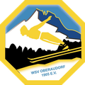 Ein gelbes Sechseck-Logo mit einem Skifahrer mitten im Sprung, verschneite Berge im Hintergrund und dem Text 'WSV OBERAUDORF 1905 E.V.' darunter.