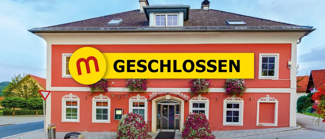 Ein rotes Gebäude mit einem gelben Schild über dem Eingang steht 'Geschlossen'. Das Gebäude hat weiße Fenster und Türen, und Blumen hängen an den Fenstern.