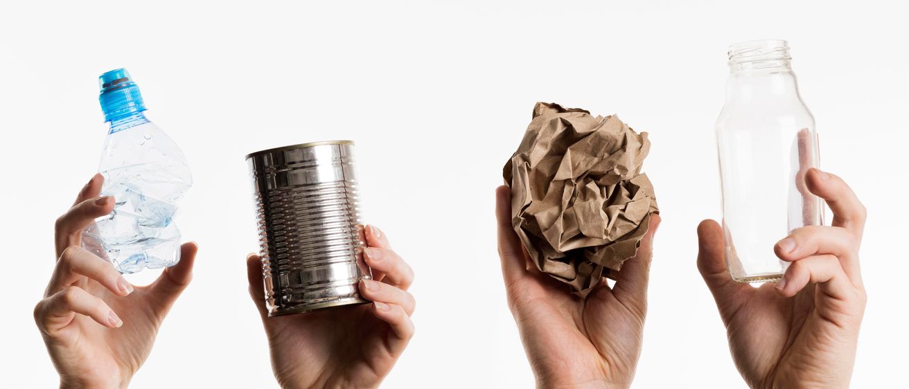 Fünf Hände halten eine Plastikflasche, eine Blechdose, zerknülltes Papier und eine Glasflasche. Jede Hand zeigt Recycling-Absicht.