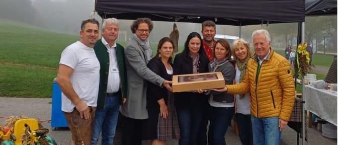 Eine Collage aus vier Bildern. Zuerst stehen Menschen in traditioneller Kleidung zusammen. Zweitens hält ein Mann eine Geschenkbox. Drittens sitzt ein Junge in einem geschmückten Wagen. Viertens fährt ein Junge einen kleinen Traktor.