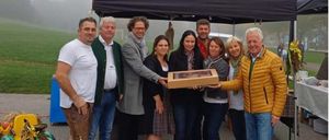 Eine Collage aus vier Bildern. Zuerst stehen Menschen in traditioneller Kleidung zusammen. Zweitens hält ein Mann eine Geschenkbox. Drittens sitzt ein Junge in einem geschmückten Wagen. Viertens fährt ein Junge einen kleinen Traktor.