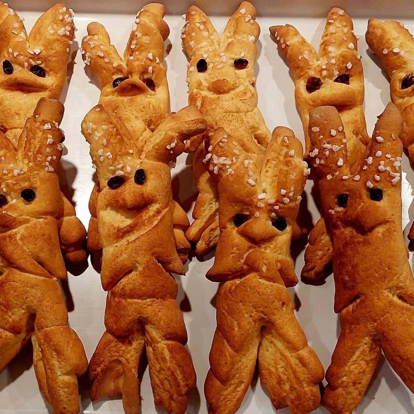 Ein Tablett mit Gebäck in Form von Hasen mit dunkler Füllung und weißen Sprenkeln obenauf. Sie haben auffällige Ohren und schwarze Augen.