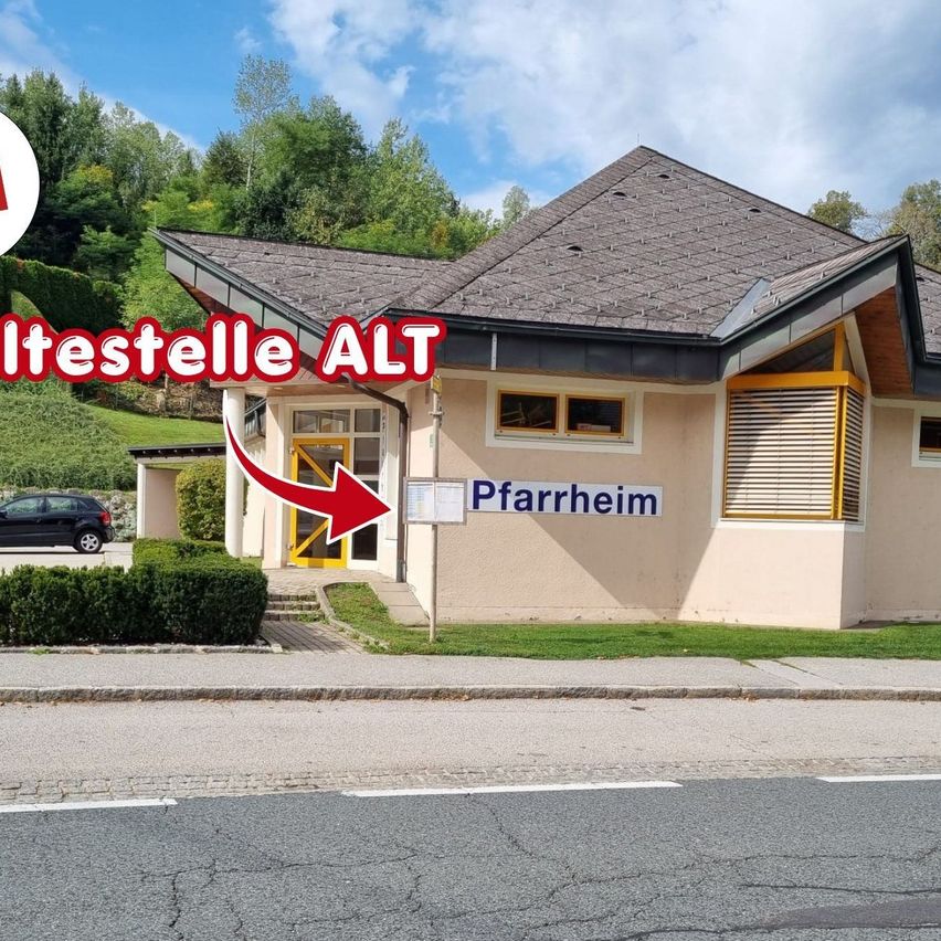 Ein Haus mit einem Schild, das 'Pfarrheim' besagt, und einem roten Pfeil darauf. Ein Auto ist in der Nähe geparkt.