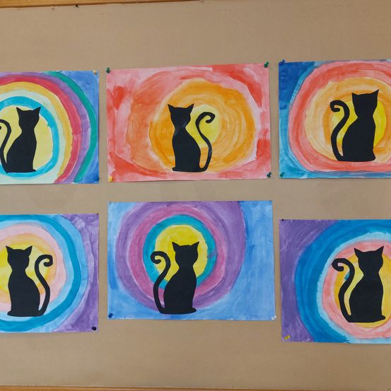 Sechs Gemälde schwarzer Katzen sind an einer braunen Wand aufgehängt. Jede Katze steht im Mittelpunkt eines kreisförmigen Musters mit verschiedenen Farben.