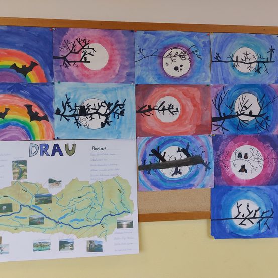 Eine Sammlung von neun Gemälden mit Schwerpunkt auf Mond, Fledermäusen und Regenbögen. Die Gemälde sind an einer gelben Wand ausgestellt.