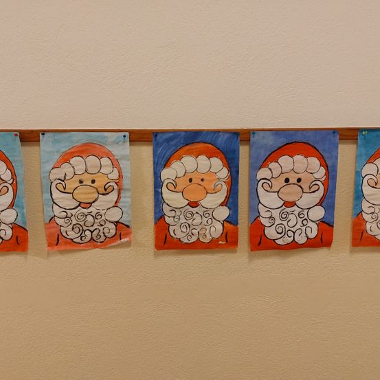 Fünf Gemälde von Santa Claus hängen an einer Wand. Jedes Gemälde zeigt ein anderes Gesicht, aber alle haben weiße Bärte und rote Mützen.