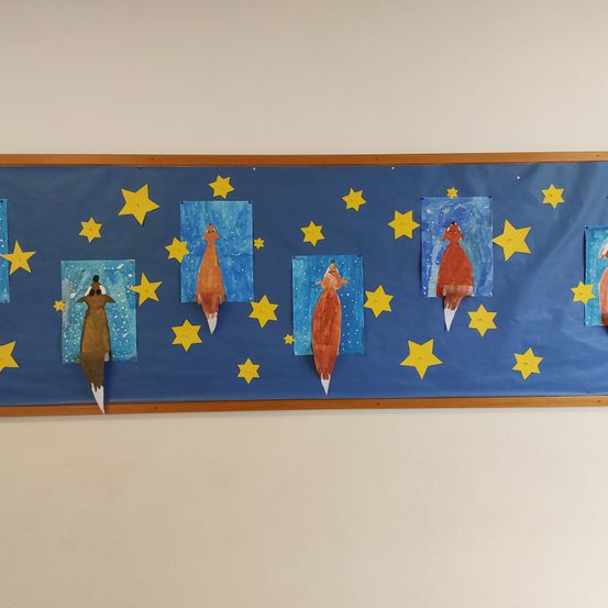 Ein blauer Bulletin-Board mit Nachthimmel-Thema zeigt fünf Gemälde von Füchsen, jedes mit einem nach oben weisenden Schwanz. Der Himmel ist mit gelben Sternen verziert.