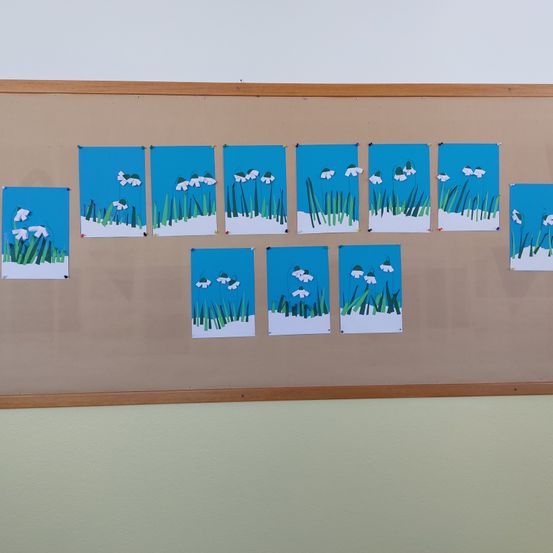 Ein Anschlagbrett mit neun kleinen blauen und weißen Bildern von Blumen im Schnee.