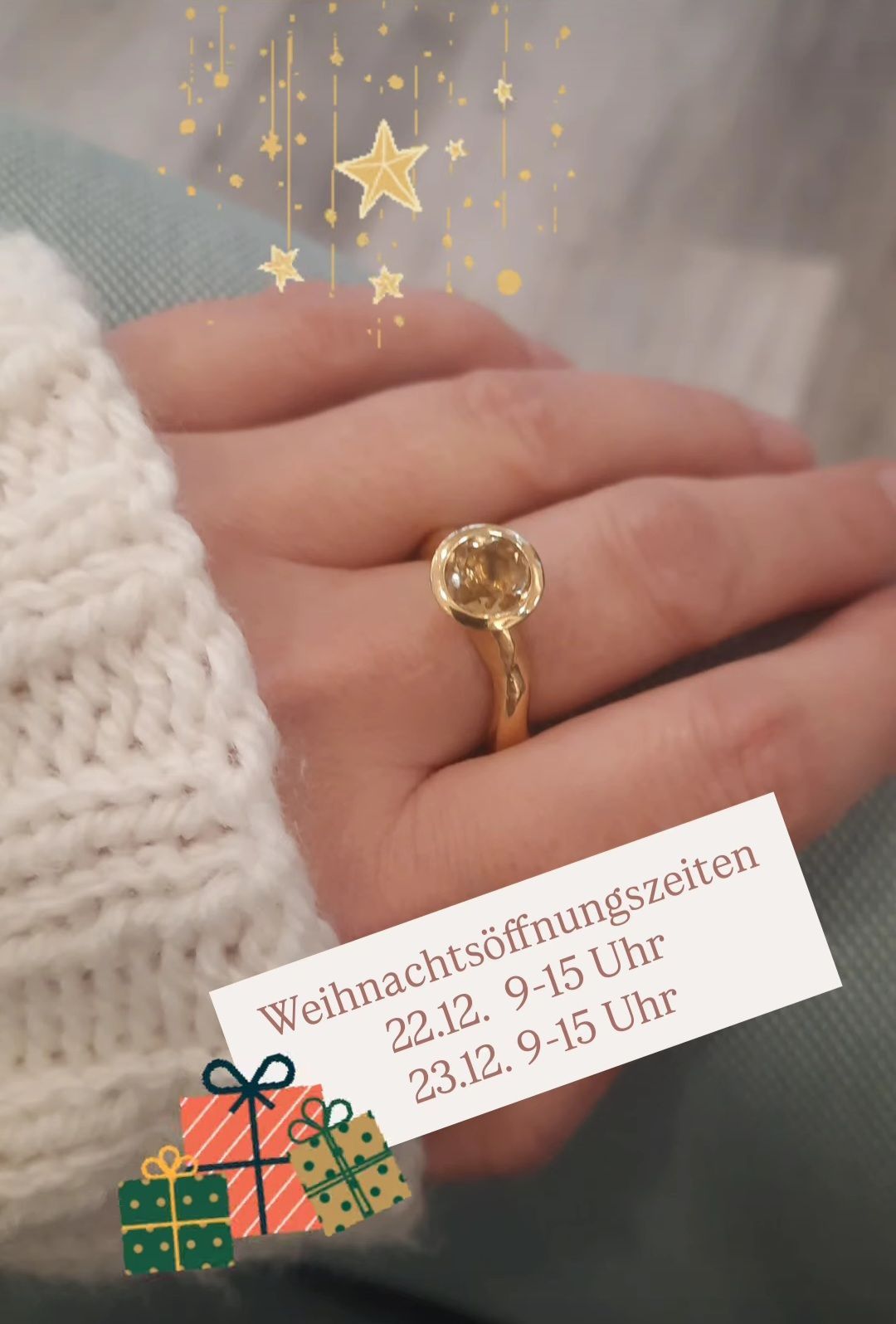 Eine Hand mit einer gestrickten Handschuh trägt einen goldenen Ring mit einem Edelstein. Ein Zettel zeigt die Weihnachtsöffnungszeiten für den 22. und 23. Dezember.