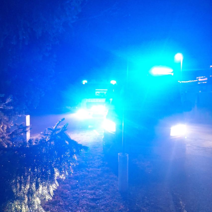 Ein Rettungsfahrzeug steht nachts am Straßenrand mit blauen Lichtern.