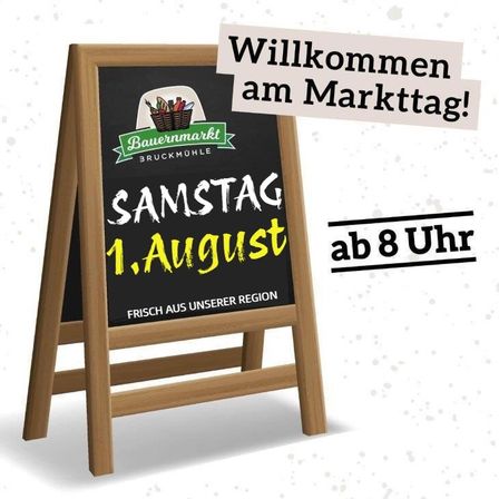 Ein Holzschild zeigt eine Marktansage auf Deutsch, die Besucher am Samstag, 1. August, ab 8 Uhr willkommen heißt. Das Schild enthält ein Logo und den Text 'FRISCH AUS UNSERER REGION'.