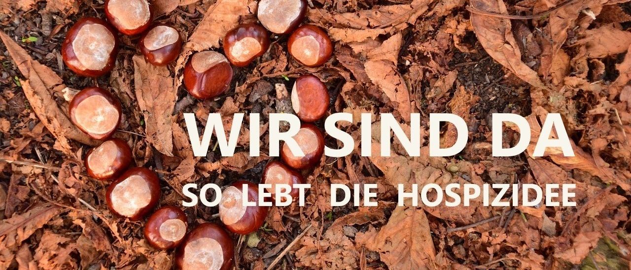 Herbstblätter und Kastanien verstreut auf dem Boden, mit einer Botschaft auf Deutsch, 'Wir sind so lebt die Hospiz'. Das Bild vermittelt eine ruhige, nachdenkliche Stimmung.