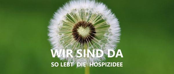 Ein Löwenzahn mit weißen Blütenblättern und einem braunen Zentrum vor einem grünen Hintergrund. Der Text lautet 'Wir sind da' und 'So lebt die Hospizdee.' Es scheint eine Werbung zu sein.