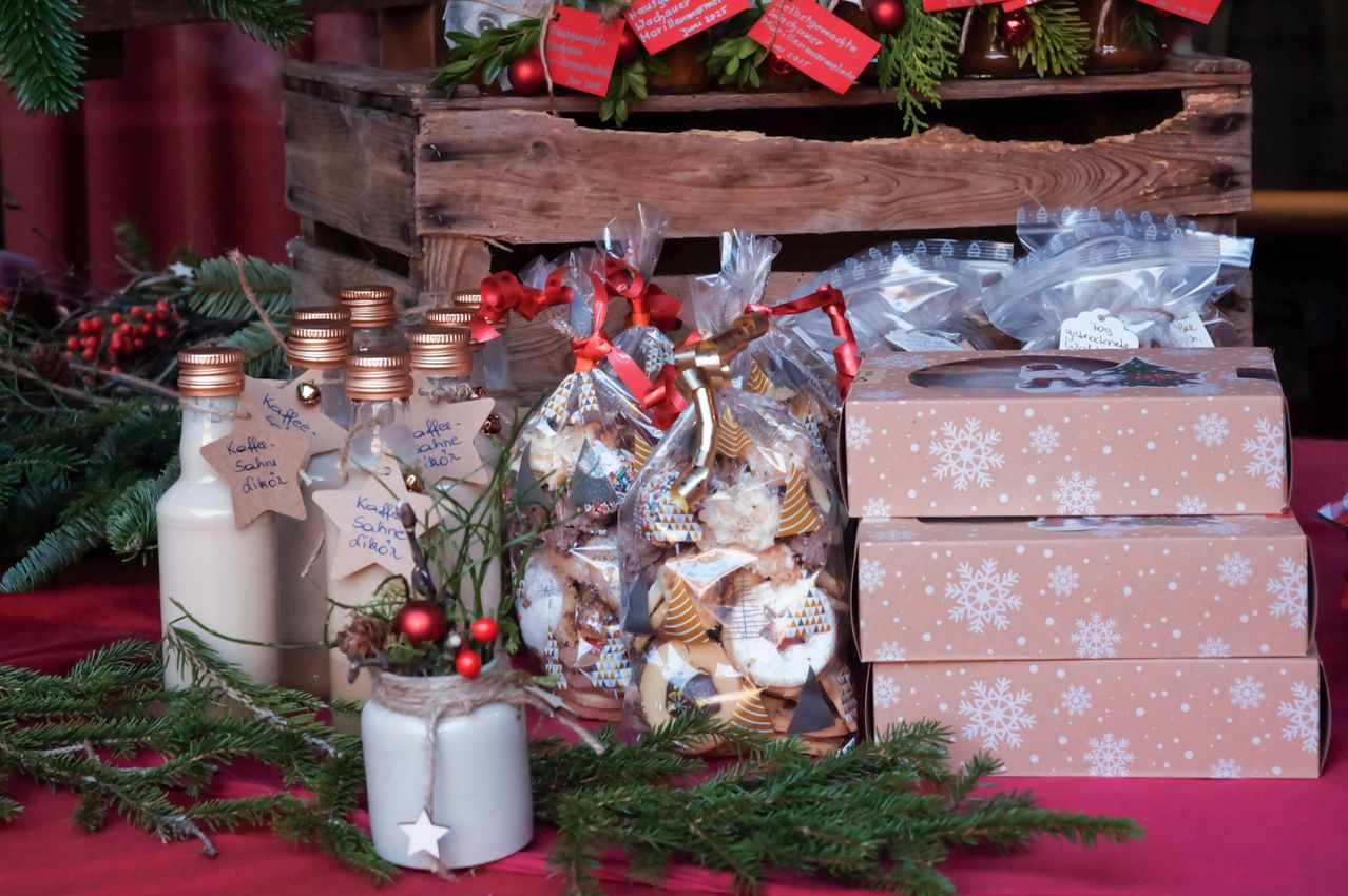 Auf einem Tisch stehen ein Kaffeeglas, kleine Flaschen und Packungen mit Keksen. Ein Holzpalette hält im Hintergrund weitere Gegenstände.