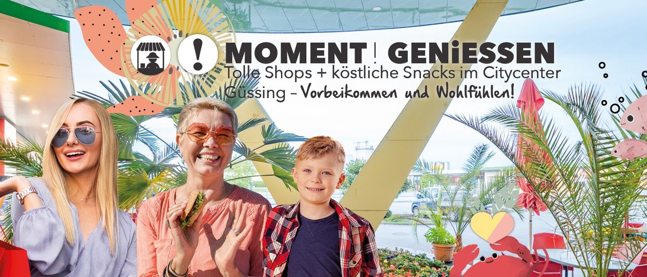 Eine lächelnde ältere Frau und ein junger Junge stehen zusammen draußen und halten Snacks. Ein Schild über ihnen wirbt mit einem farbenfrohen Sonnengrafik für 'MOMENT GENIES'.