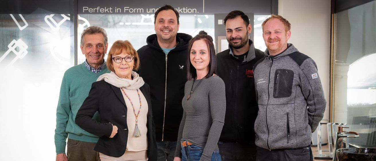 Eine Gruppe von Menschen posiert für ein Foto vor einem Schild, das Perfekt in Form und Funktion besagt.