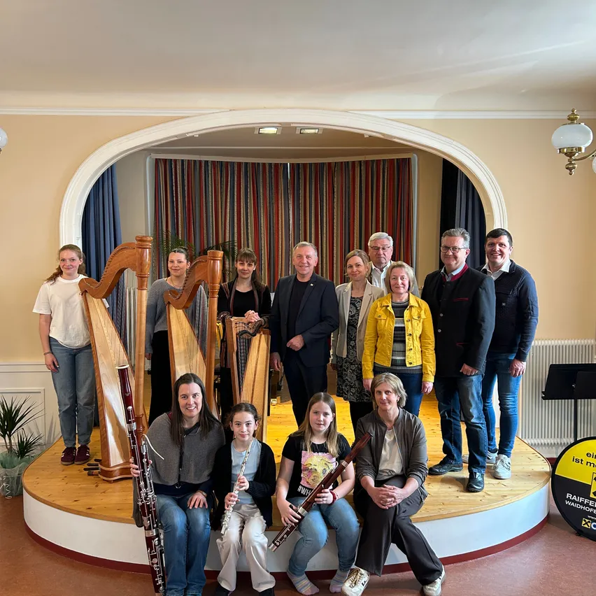 Eine Gruppe von Menschen posiert für ein Foto in einem Raum mit Musikinstrumenten. Sie lächeln und scheinen Musiker zu sein.