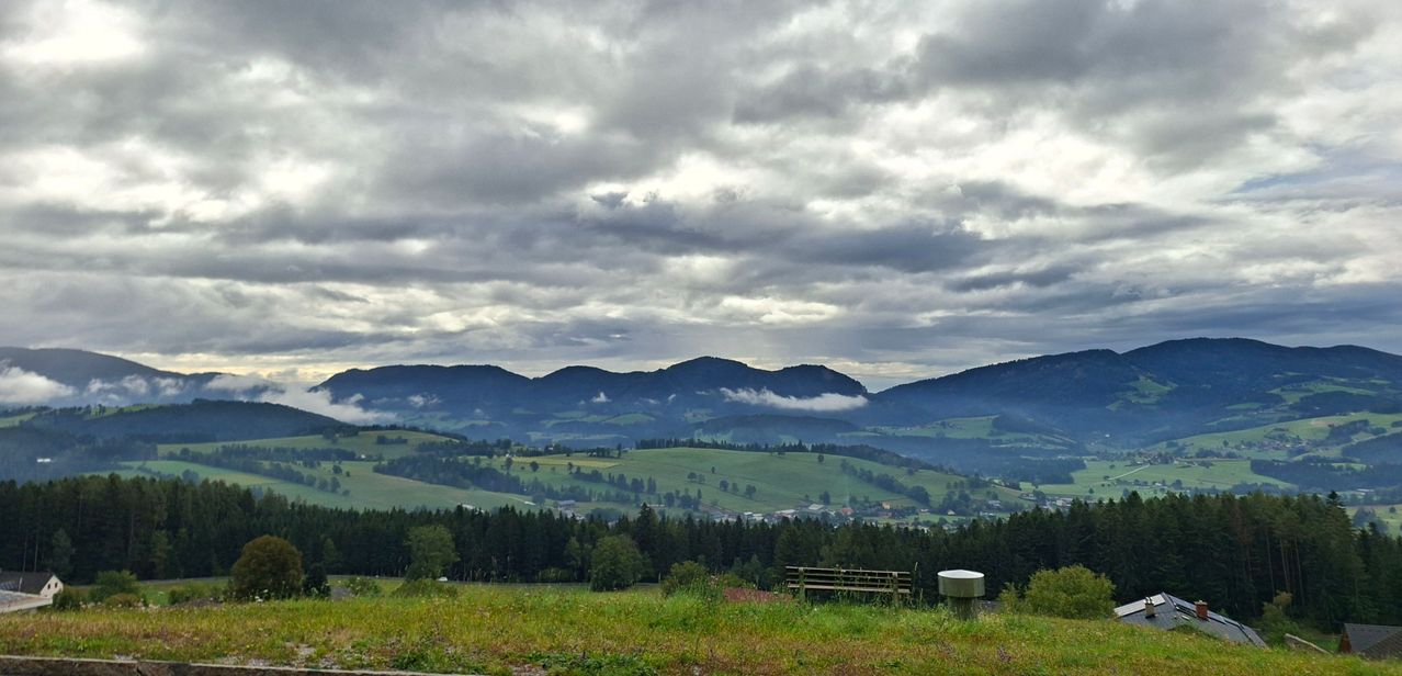 Bergpanorama in Oberösterreich mit Wolken und Nebel über grünen Hügeln