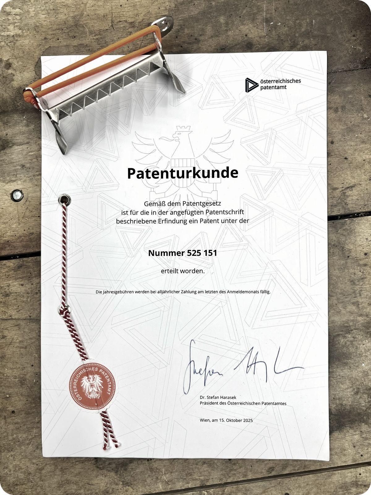 An Austrian patent certificate on a wooden surface, featuring a red seal, the number 525 151, and a signature. It is for an invention described in the patent script.